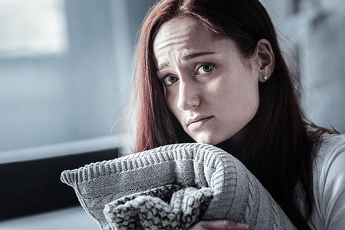 Anxious woman holding blanket may need an addiction social anxiety disorder treatment program