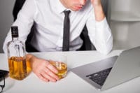 man with a laptop and a drink in his hand