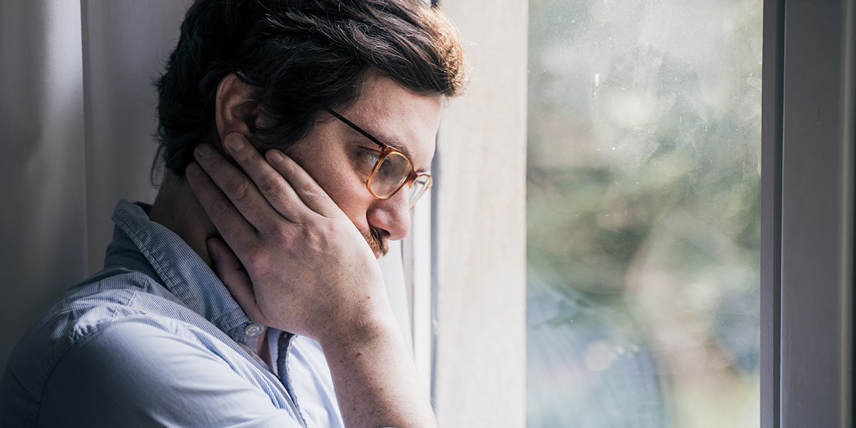 man looking out window concerned about how to fight drug cravings