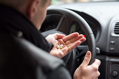 Man taking pills behind the wheel surely engaging in drugged driving