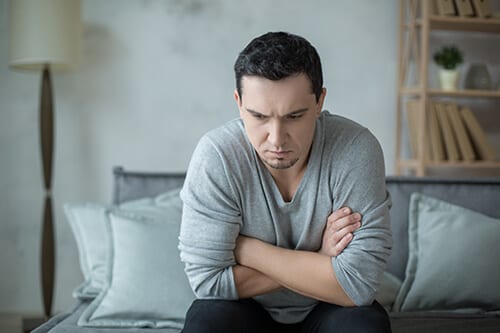 Anxious looking man on sofa needs the anxiety treatment program at Beaches