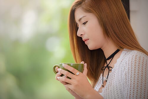 Woman drinking coffee wondering about why she is dating someone in drug addiction recovery