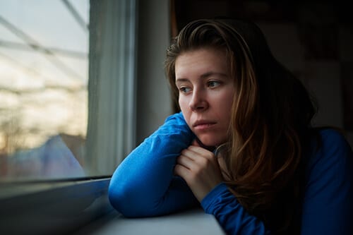 Concerned girl looking out window wants to know how to deal with anxiety without drugs