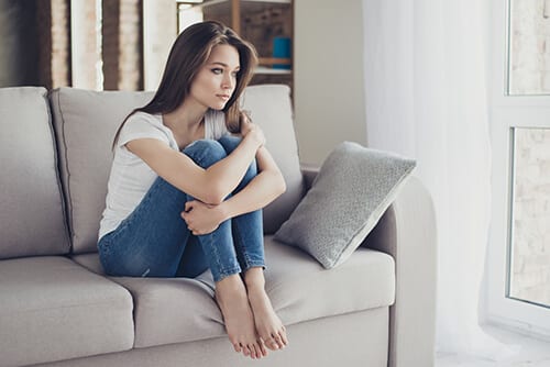 Woman on sofa curled up wondering is drug addiction a choice