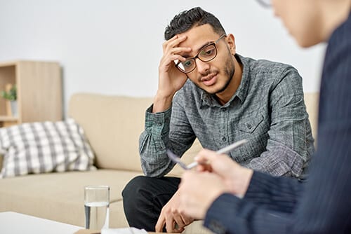 Man with glasses talking to intake counselor about drug rehab programs for men