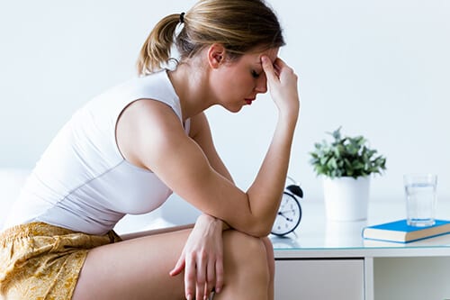 Worried woman with hand to face experiencing ghb drug effects