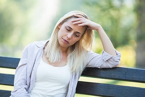 Distressed woman on park bench knows about the relapse rates for drug addiction personally