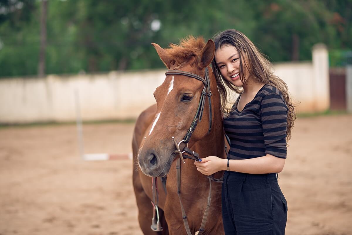a woman smiles next to a horse thinking about the benefits of equine therapy