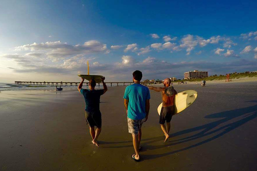 Three men walking along Jacksonville beach with surfboards