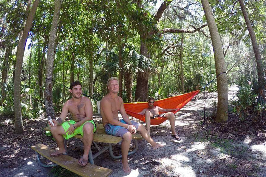 Three men relaxing under the trees on a beach