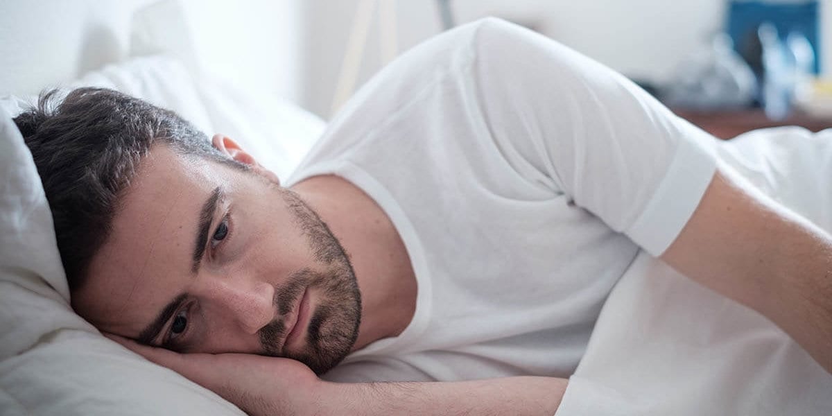 Man laying in bed wonders what is clinical depression