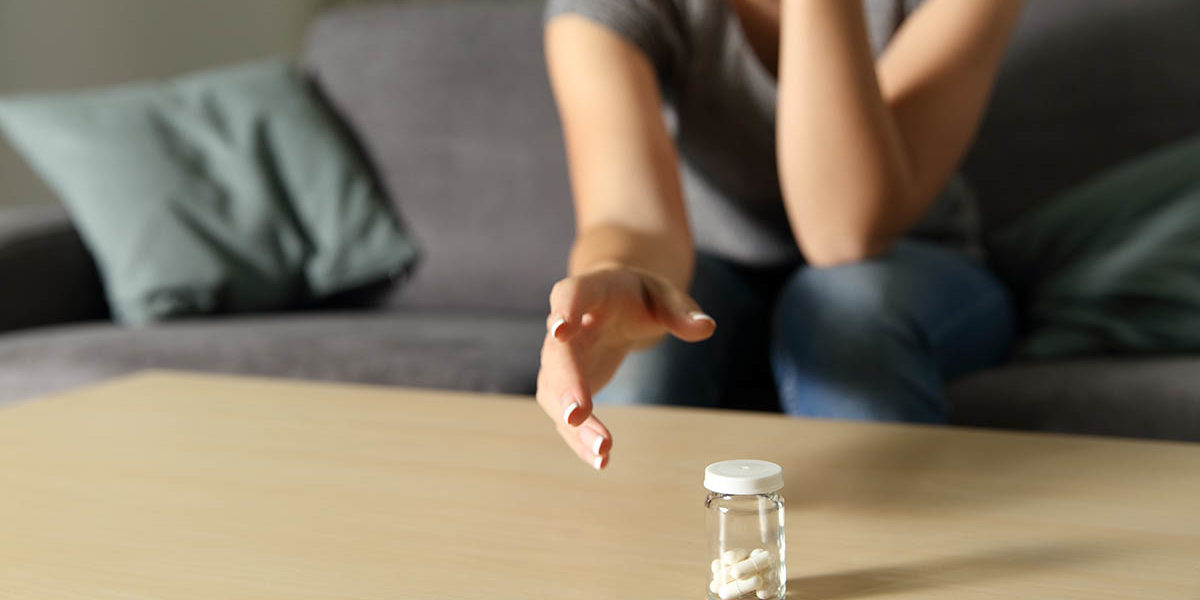 woman reaching for pills suffers from anxiety and addiction