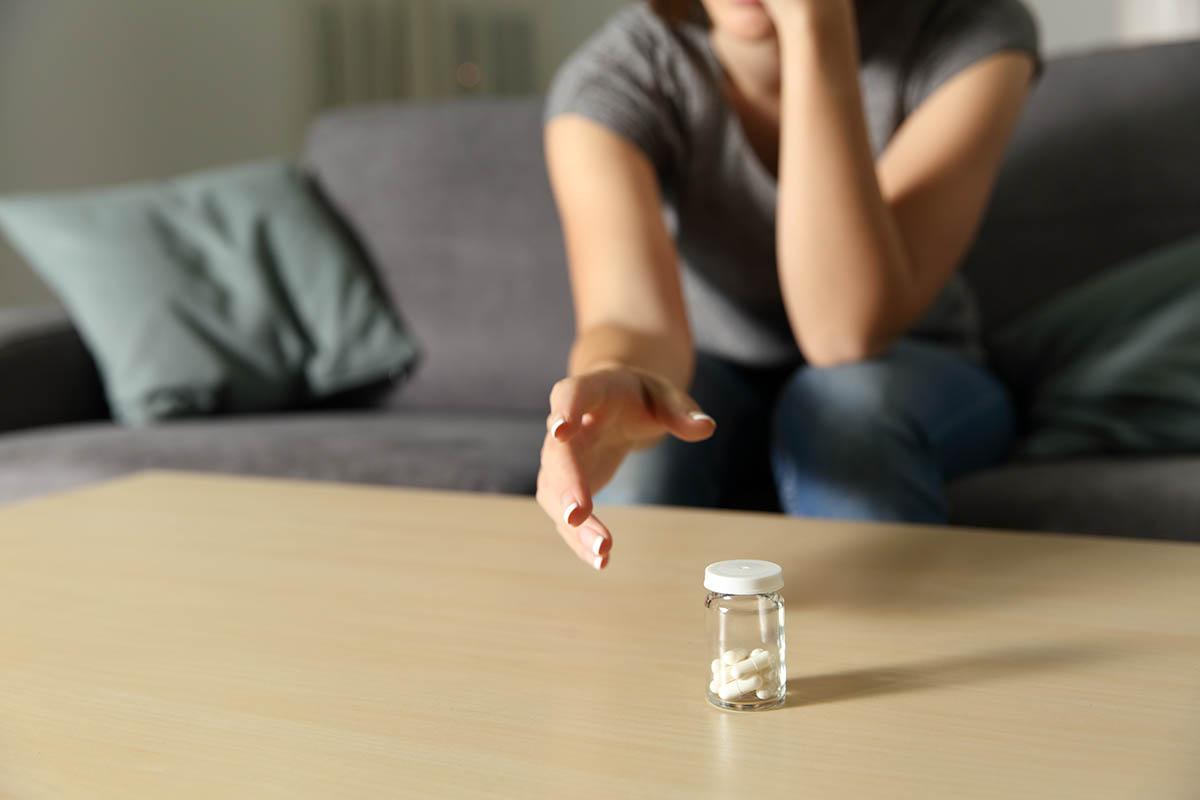 woman reaching for pills suffers from anxiety and addiction