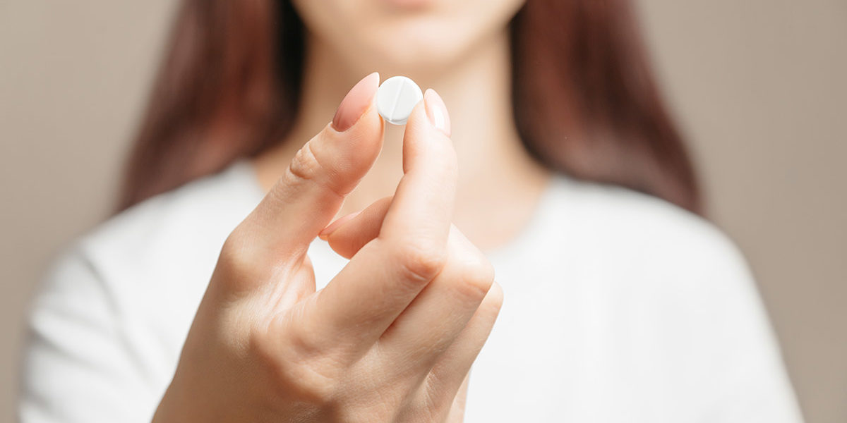 a woman holding a pill showing what are synthetic opioids