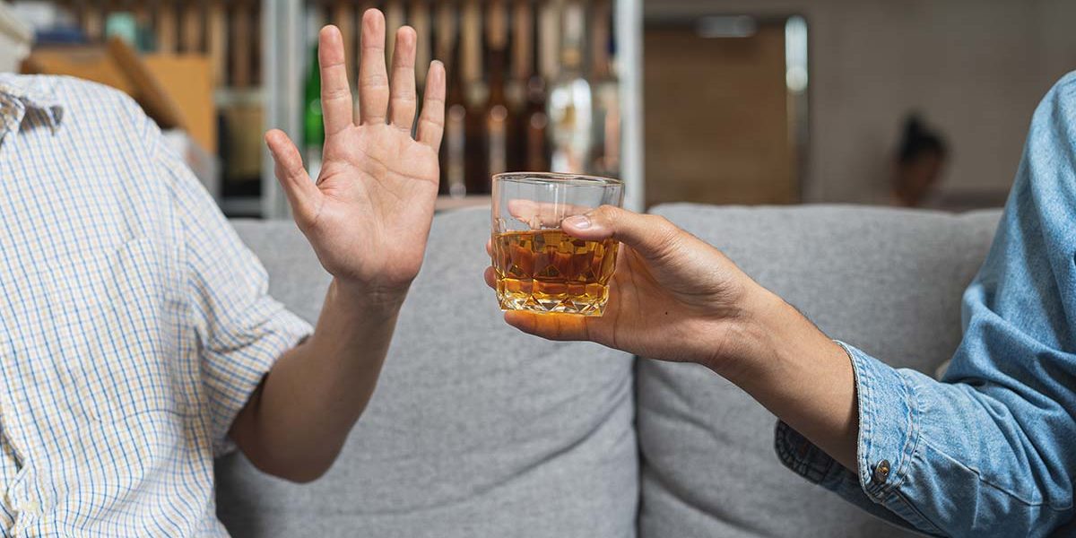 man putting a hand up to say no to suggested glass of alcohol after treatment at the alcohol rehabilitation center in florida