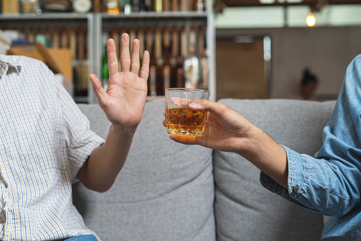 man putting a hand up to say no to suggested glass of alcohol after treatment at the alcohol rehabilitation center in florida
