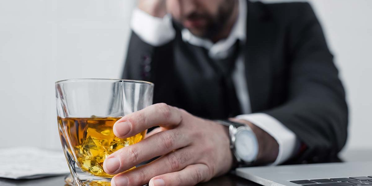 businessman drinking scotch at work needing executive alcohol rehabilitation