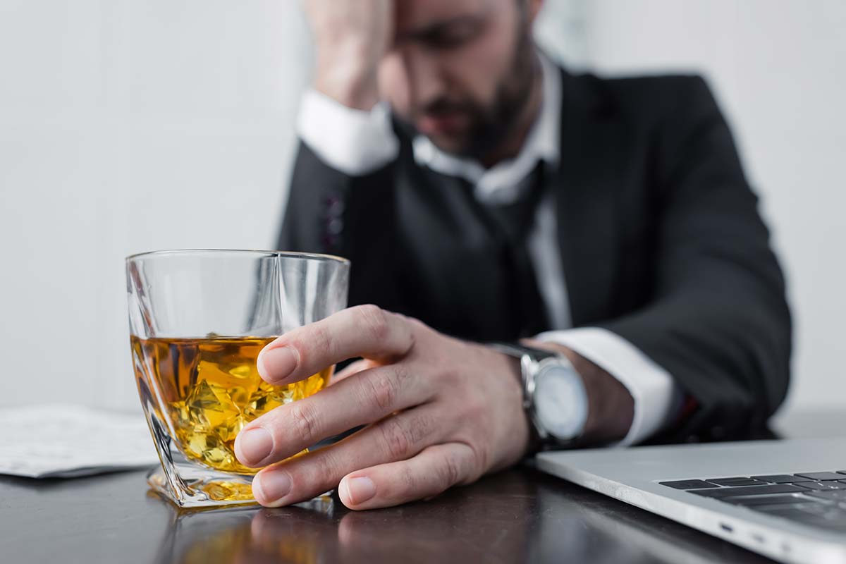 businessman drinking scotch at work needing executive alcohol rehabilitation