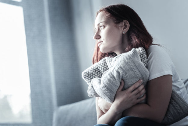 woman clutching pillow worried about addiction and your physical health