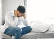man on bed with head in hands concerned about compromised immune system