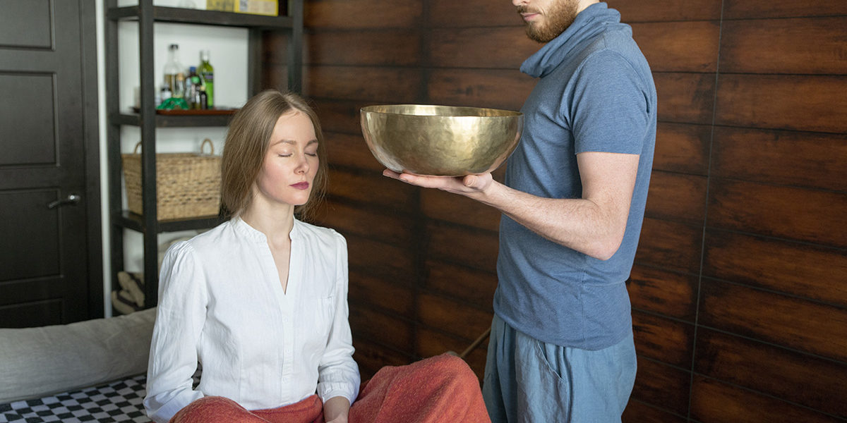 man holding a bowl for meditating woman in holistic drug therapy
