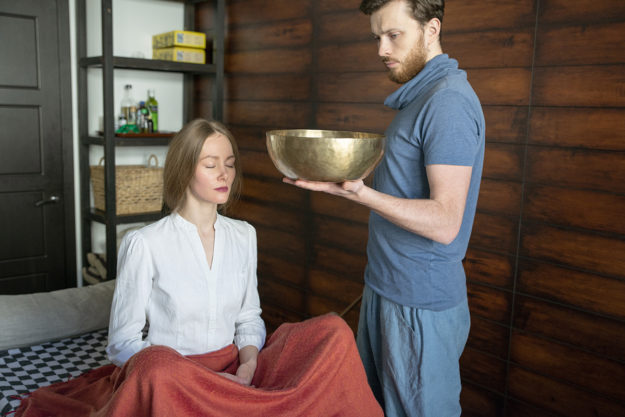 man holding a bowl for meditating woman in holistic drug therapy