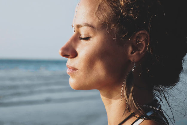 woman with eyes closed at the beach using techniques from Mindfulness Based Stress Reduction Therapy