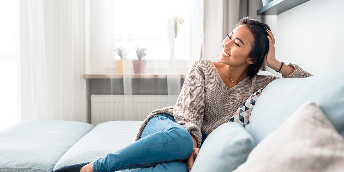 woman smiling on couch after visiting the Outpatient Care Center