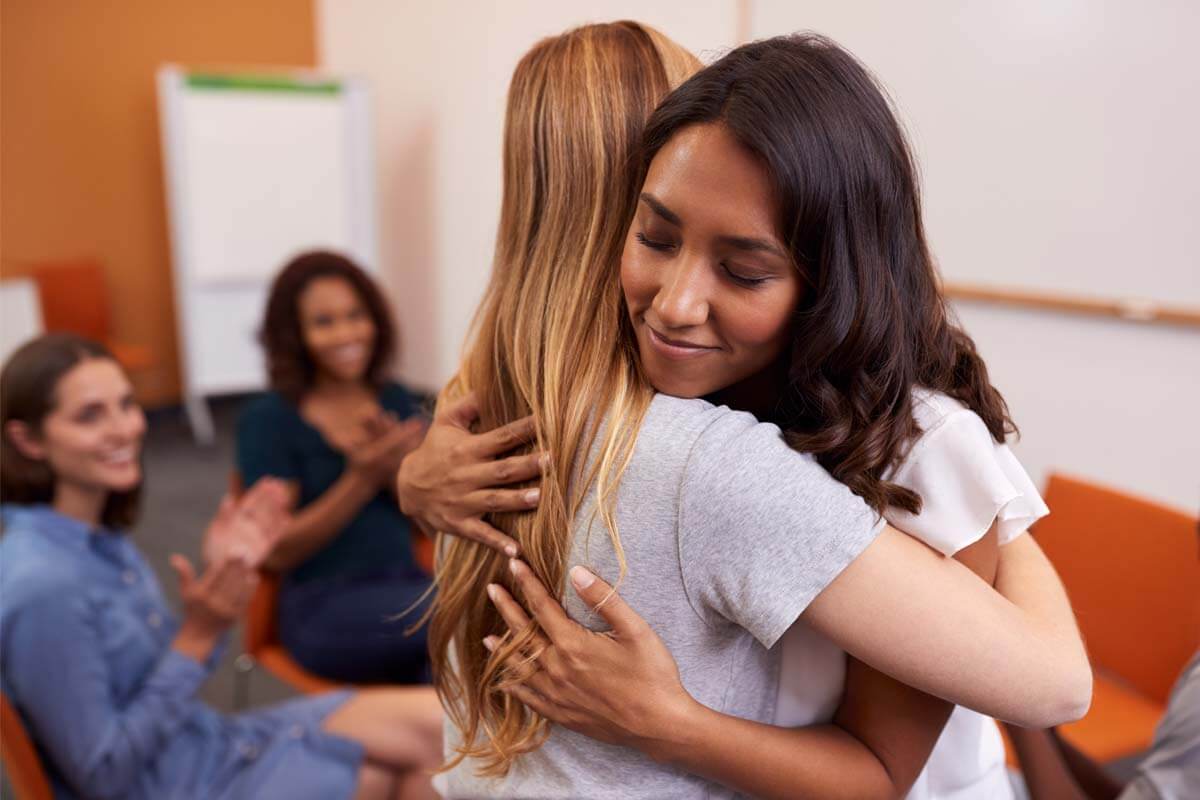 two women hugging to support each other during the Jacksonville women's rehab program