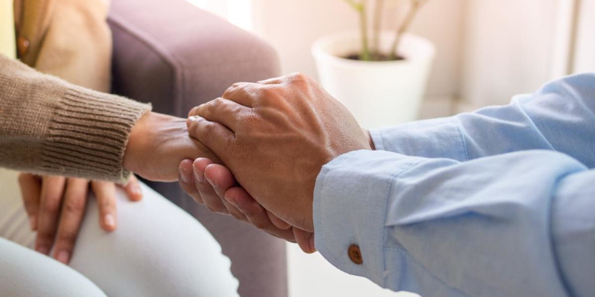 man holding woman's hand helping them with addiction