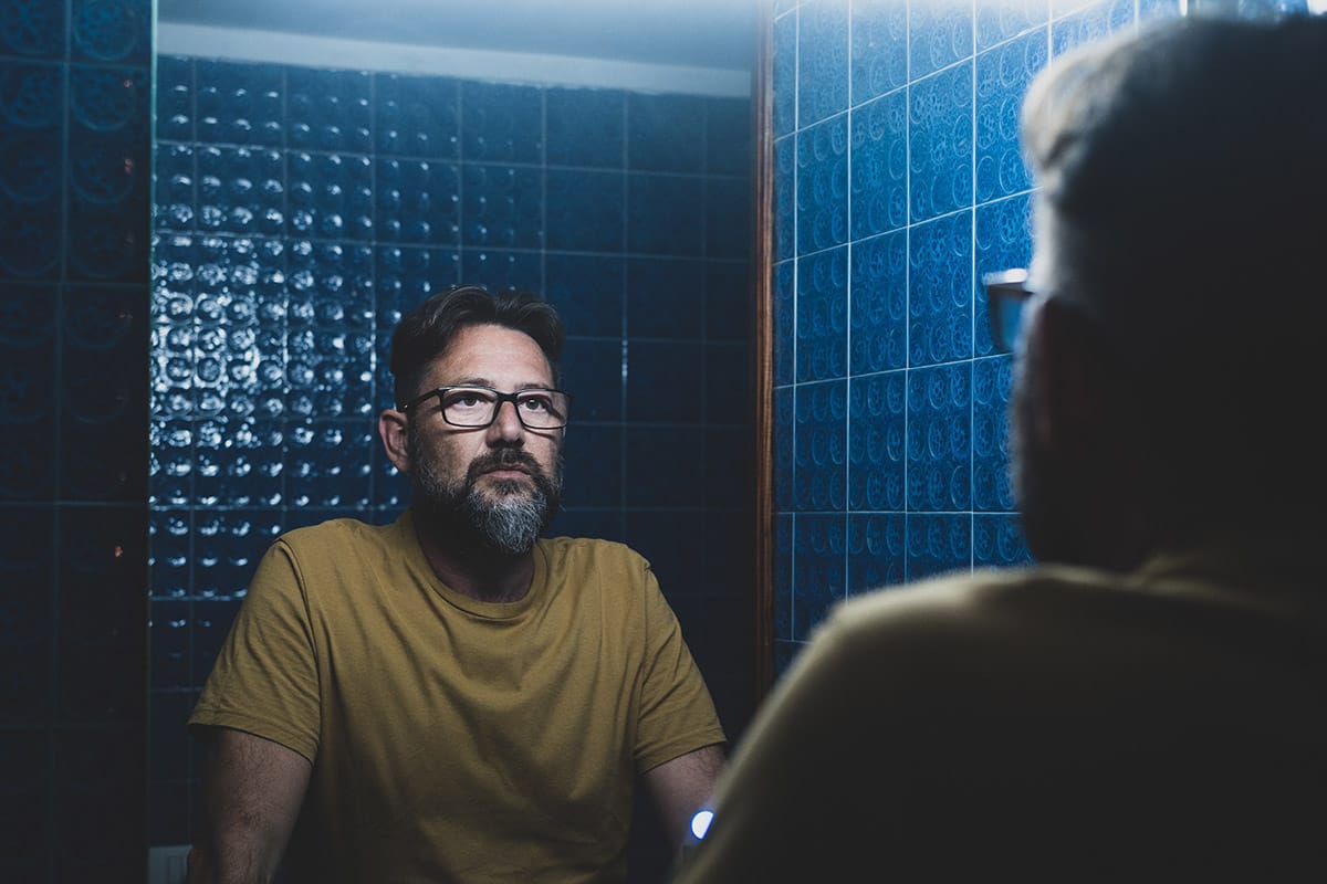 Man looking in mirror and thinking about street names for drugs