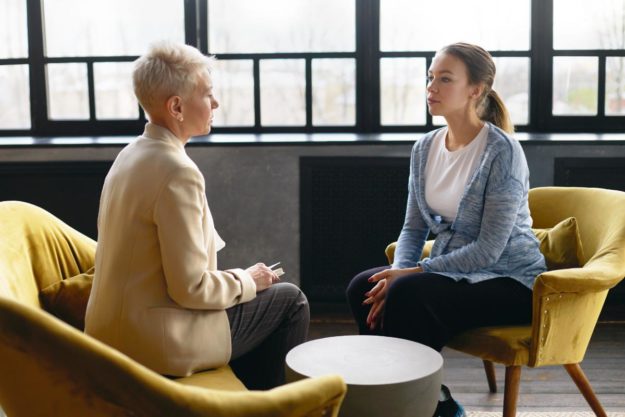 two women talking on yellow chairs